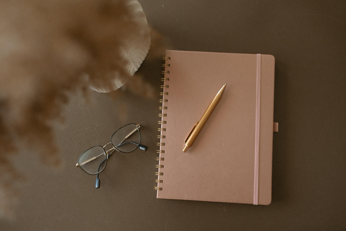 A calm flatlay of a notebook and simple objects, evoking focused, grounded sport and performance therapy at Anchor & Bloom