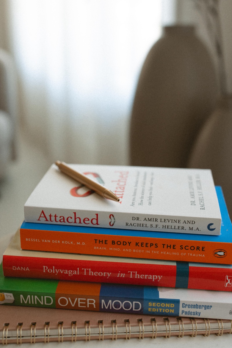 A grounded stack of books on a calm surface, evoking steady, judgment-free men's mental health therapy at Anchor & Bloom