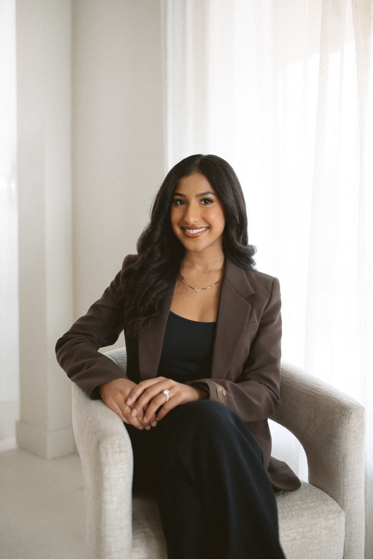Mahima Chauhan smiling while seated in an armchair