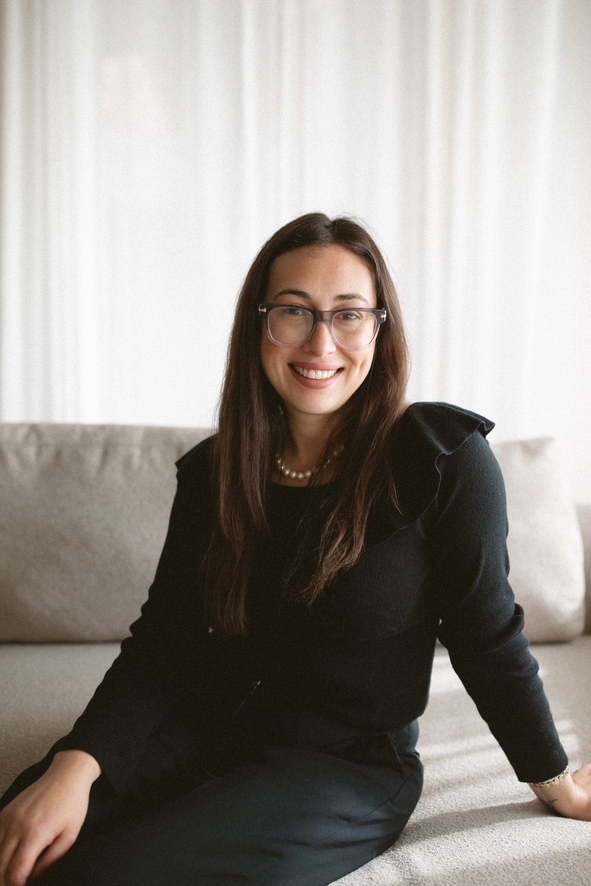 Natalie Besharat smiling while seated on a sofa