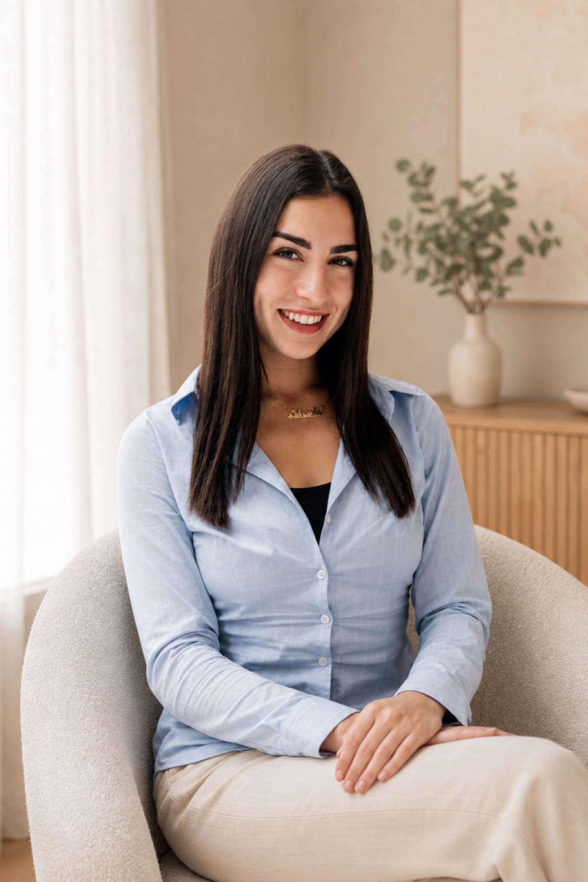 Nicole Lerman, Registered Psychotherapist (Qualifying), seated in a warm therapy setting